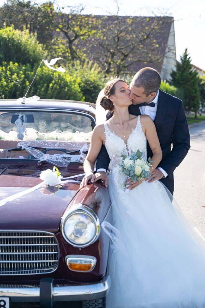 Un baiser romantique devant leur voiture capturé par Arnaud M lors des photos de mariage à La Ferté-Gaucher pour Jason et Mathilde.