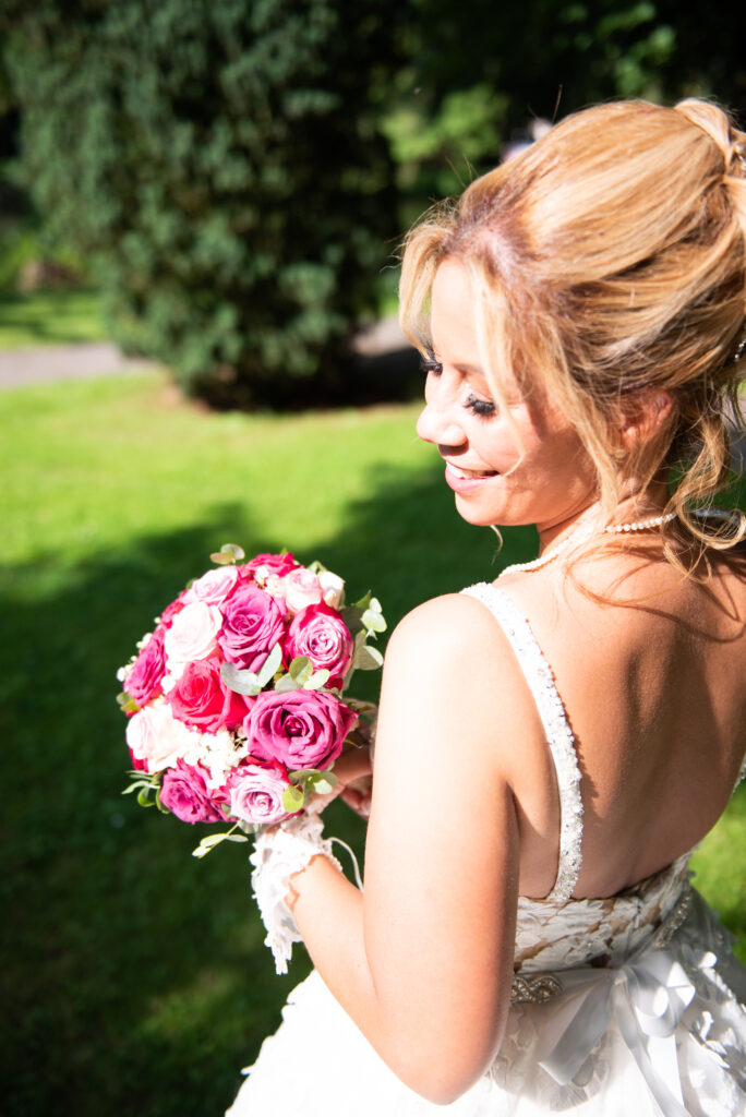 Mariage de Tania et Mickael à La Ferté-sous-Jouarre, portrait lumineux de Tania avec son bouquet de roses dans le parc des Capucins.